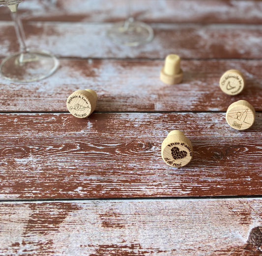cinq bouchons en bois gravés avec un verre de vin sur une table en bois