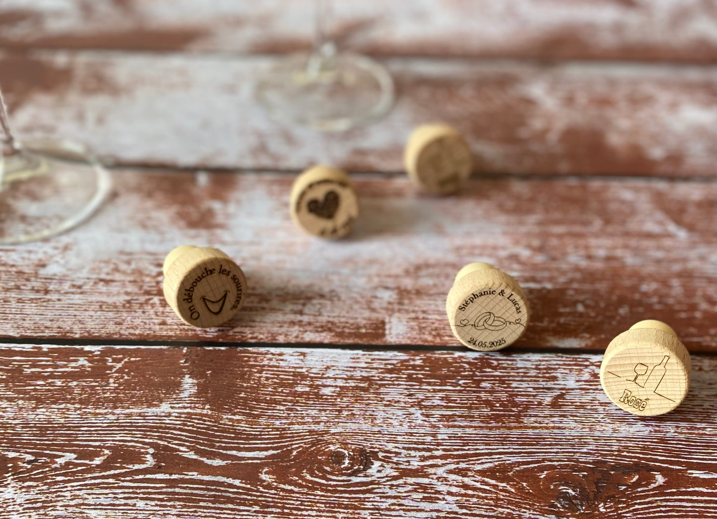 cinq bouchons en bois gravés avec un verre de vin sur une table en bois