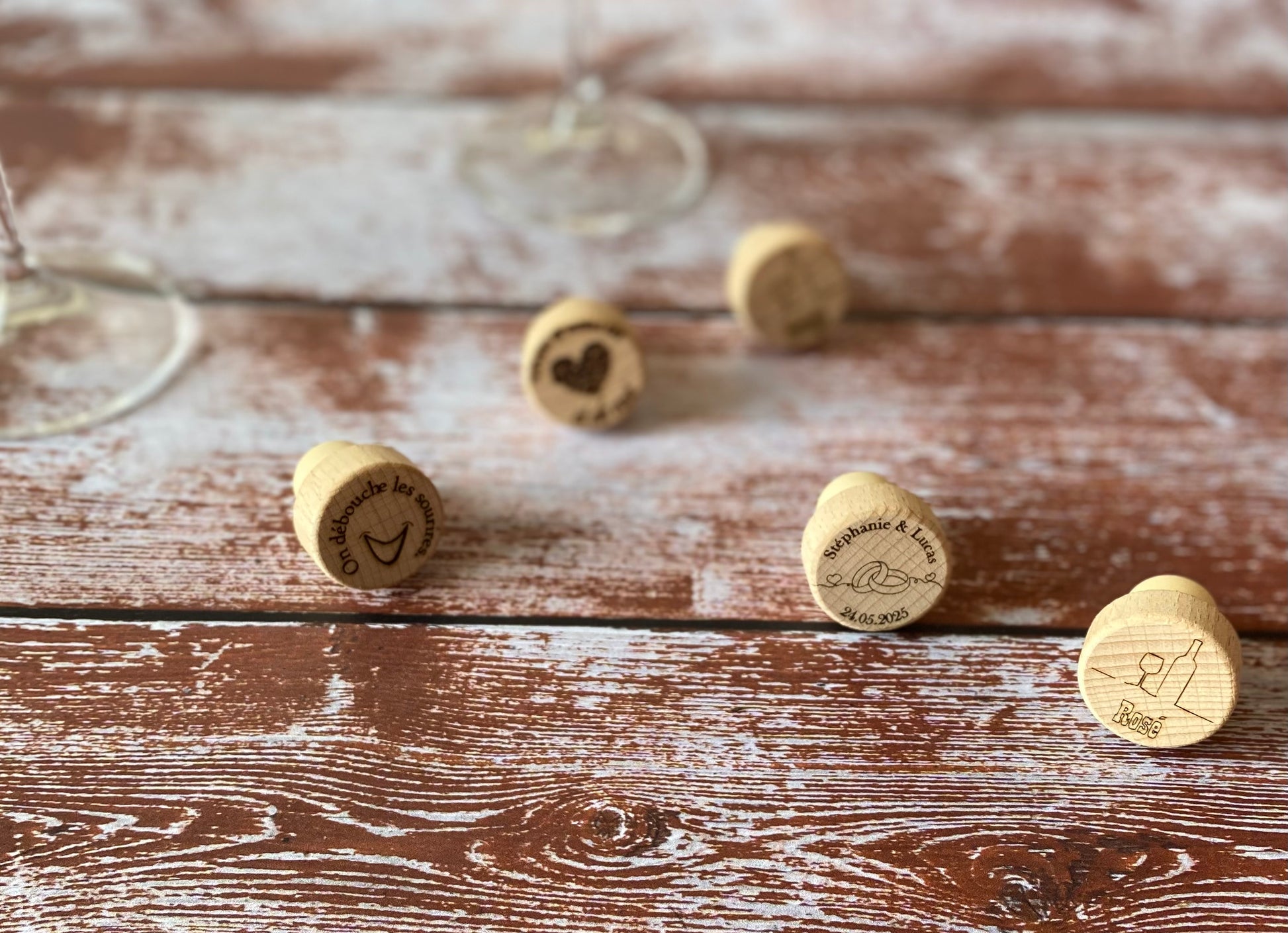 cinq bouchons en bois gravés avec un verre de vin sur une table en bois
