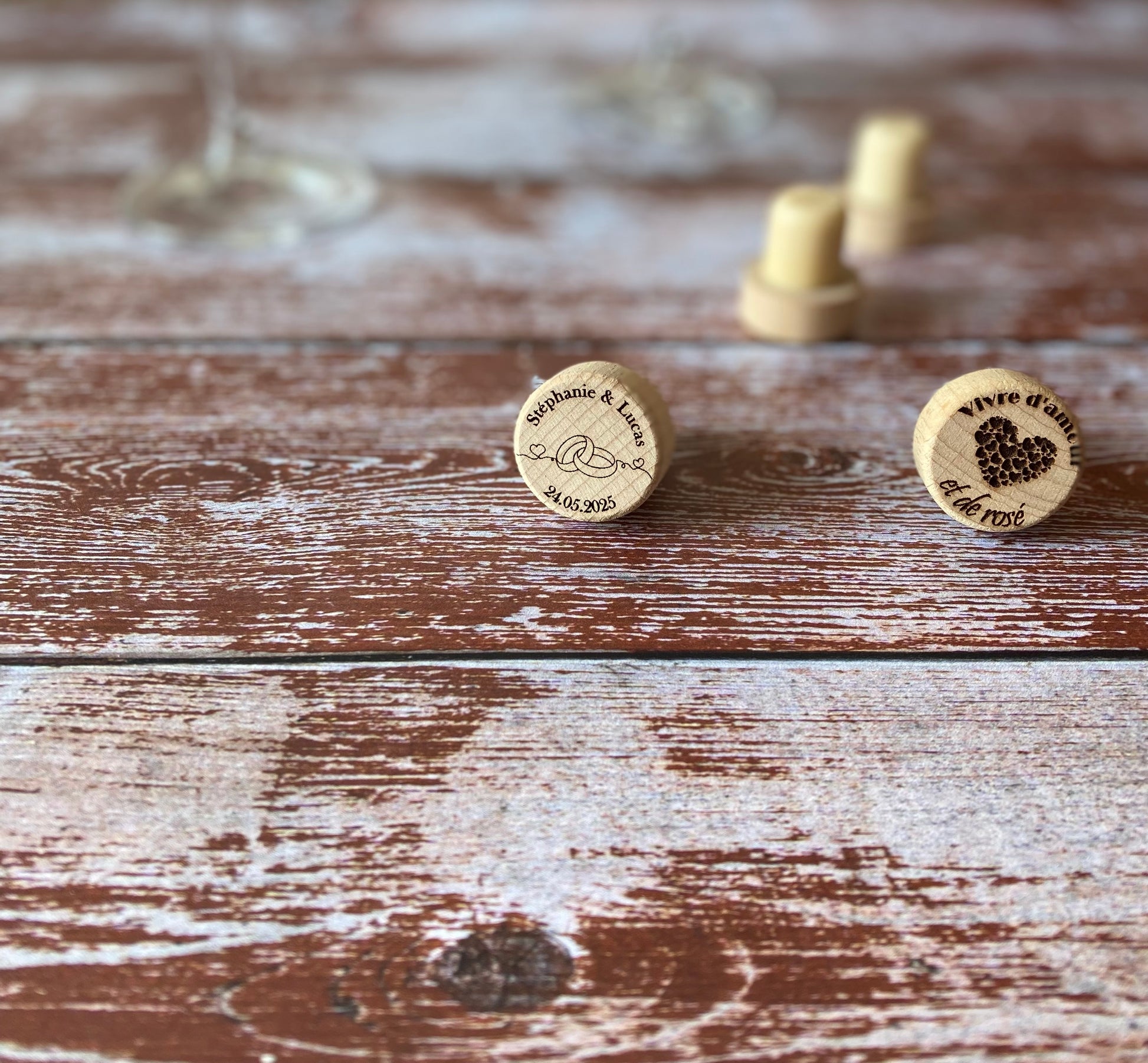 deux bouchons en bois gravés avec un verre de vin sur une table en bois